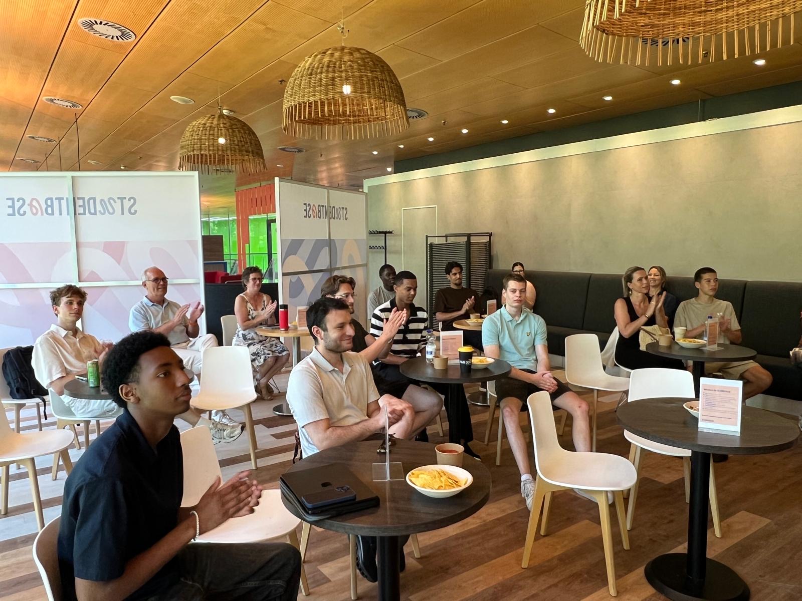 A small group of students listens to a presentation in a restaurant